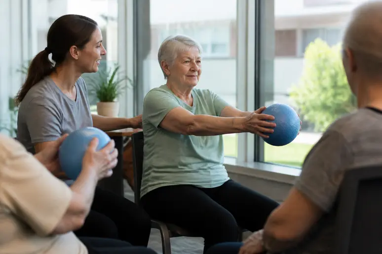 Séance de gym douce assise avec un ballon léger pour la motricité en EHPAD