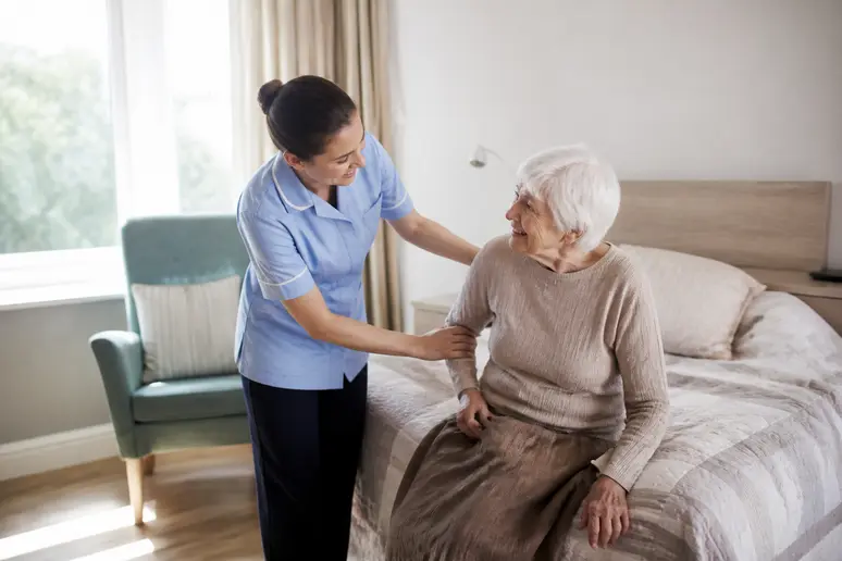 Aide-soignante accompagnant une personne âgée dans sa chambre pour le lever matinal