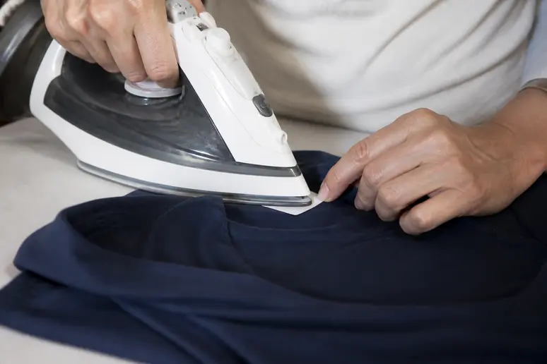 Pose d'une étiquette thermocollante pour le marquage linge ehpad à l'aide d'un fer chaud.