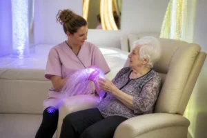 Une soignante accompagne une résidente lors d'une séance de snoezelen ehpad avec un éclairage apaisant.