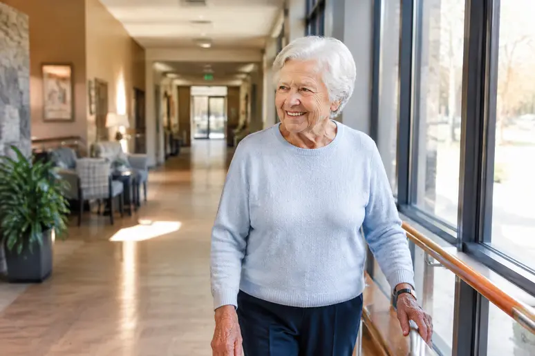 Résident senior se déplaçant dans un couloir lumineux d'une colocation senior.