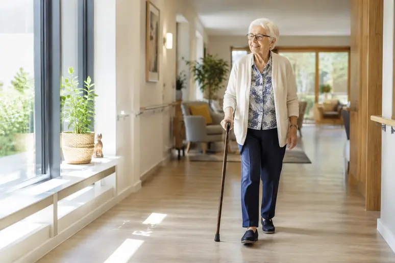 Résident senior marchant dans le couloir lumineux d'une résidence services seniors moderne
