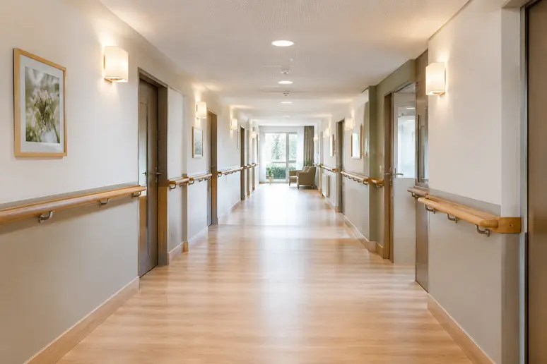 Couloir sécurisé d'une unité protégée en EHPAD avec des mains courantes en bois