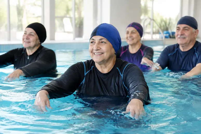 Participants pratiquant l'aquagym senior dans un bassin peu profond avec un encadrement adapté