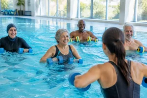 Un groupe de seniors participe à un cours d'aquagym senior dynamique dans une piscine lumineuse.